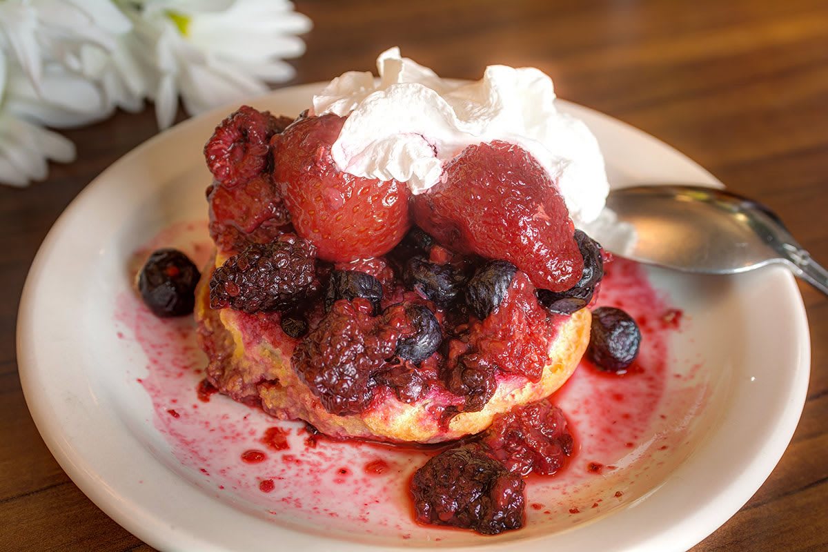 A delicious pancake topped with a medley of berries and a dollop of whipped cream.