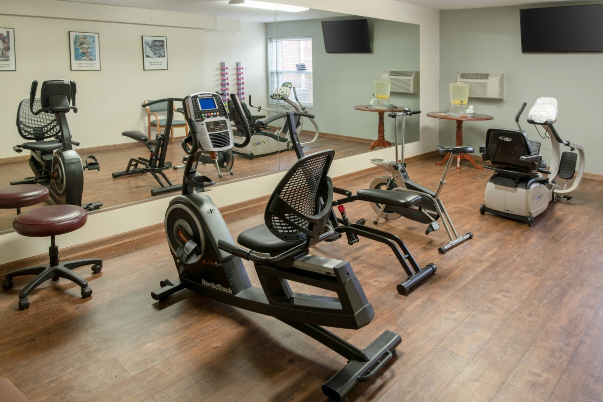 A small gym with exercise equipment including a treadmill and stationary bike, featuring mirrors on the walls.