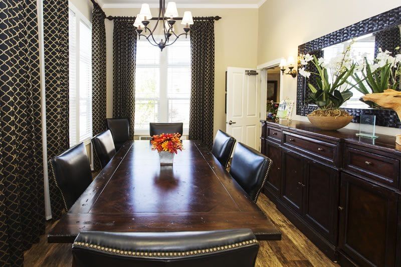 A well-decorated dining room featuring a long wooden table, leather chairs, and a chandelier.