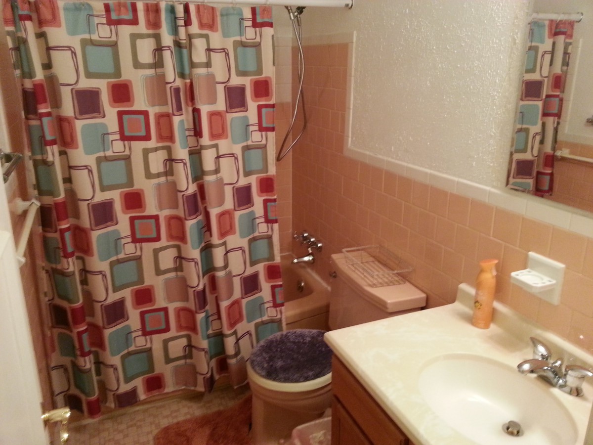 A bathroom with colorful square-patterned shower curtain and peach-colored tiles.