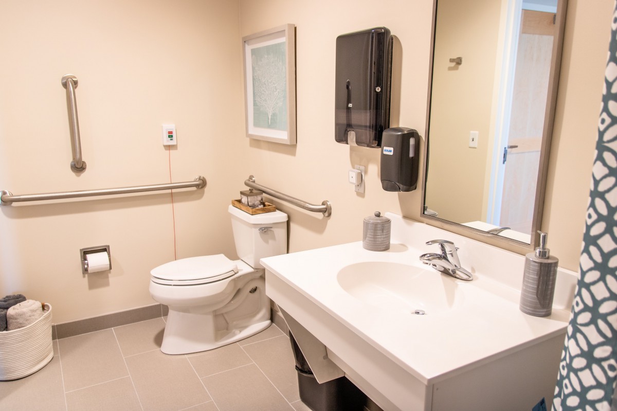 A clean and accessible bathroom with a toilet, sink, and grab bars.