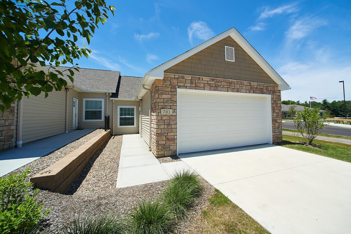 A suburban house with a garage and a driveway under a clear blue sky.