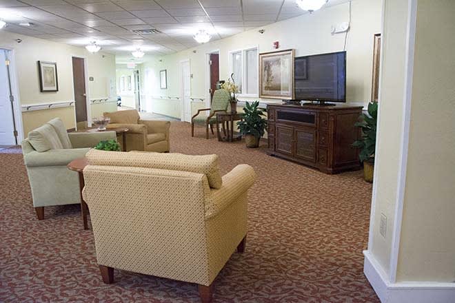A cozy living room area with comfortable chairs and a TV, along with a view down a hallway.