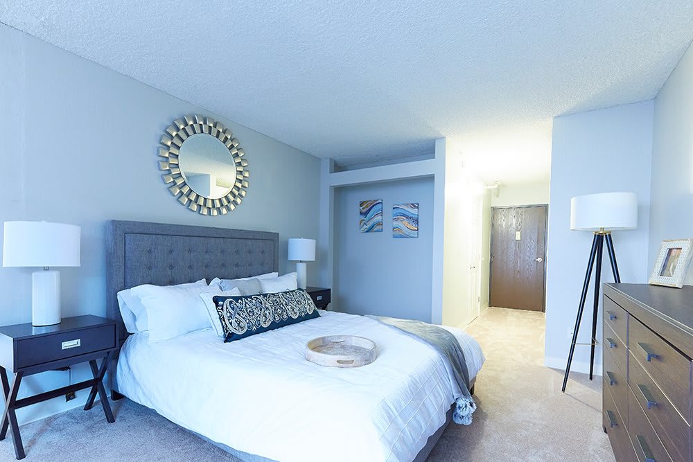 A modern bedroom with stylish decor featuring a large bed, decorative mirror, and soft lighting.