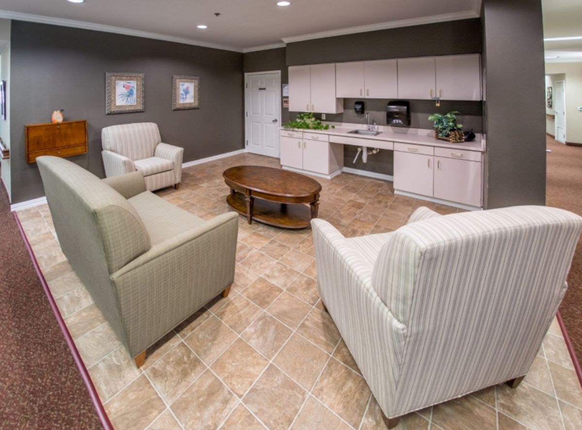 A cozy living area with armchairs, a sofa, and a kitchenette.