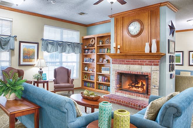 A cozy living room featuring a fireplace, bookshelves, and comfortable seating.