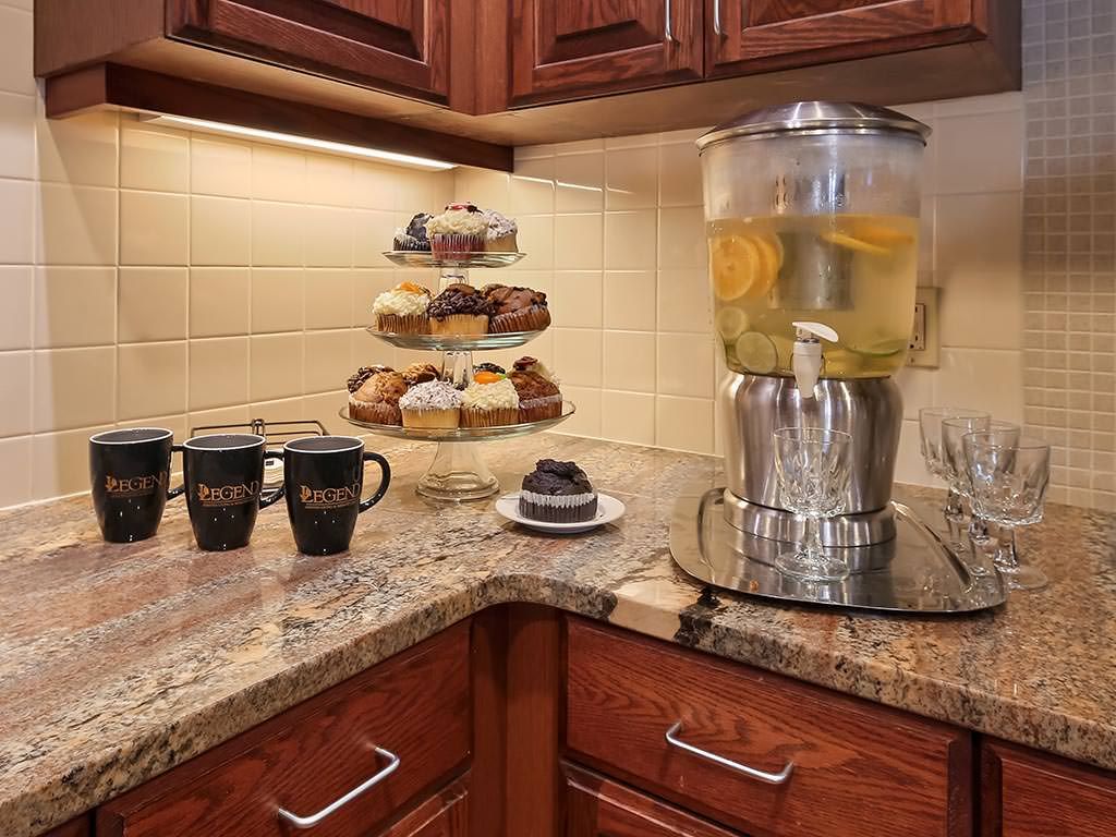 A cozy kitchen setup with a beverage dispenser, mugs, and an assortment of pastries on display.