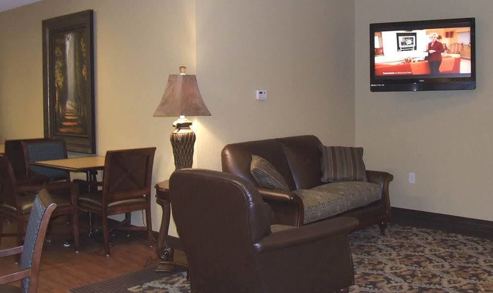 A cozy living room featuring a sofa, chair, lamp, and television.