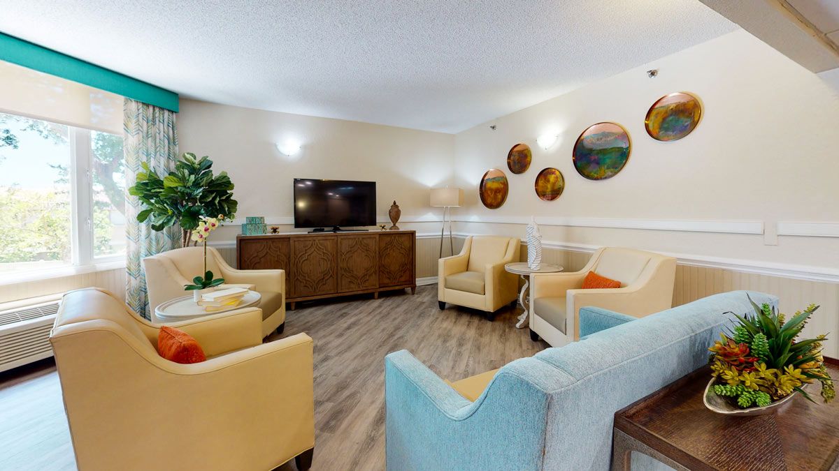 A cozy living room with comfortable seating, a TV, and decorative wall accents.