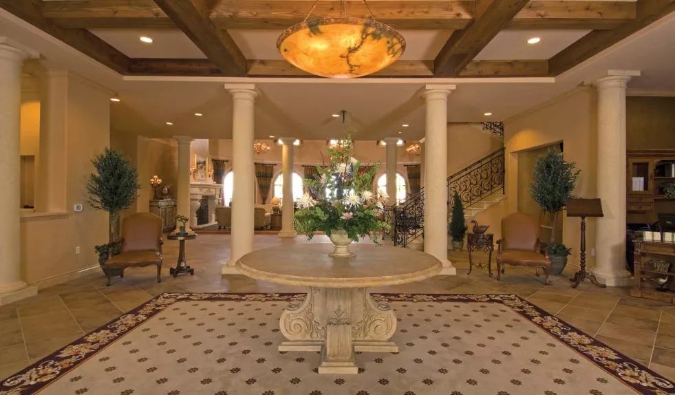 A luxurious foyer with elegant decor, featuring a central table and chandelier.
