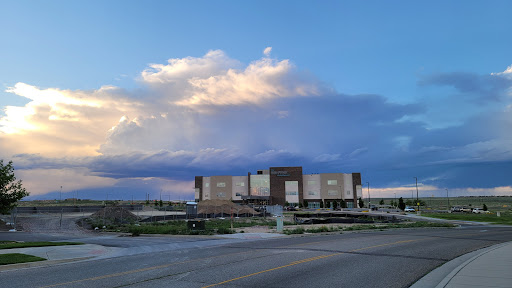 A modern building under a dramatic sky with fluffy clouds, showcasing an expansive landscape.