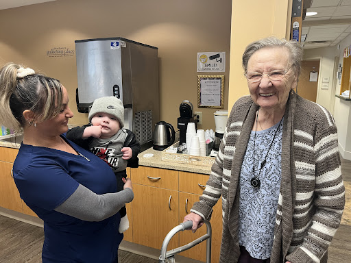 A heartwarming moment shared between a caregiver, an elderly woman, and a baby, highlighting the joy of connection across generations.