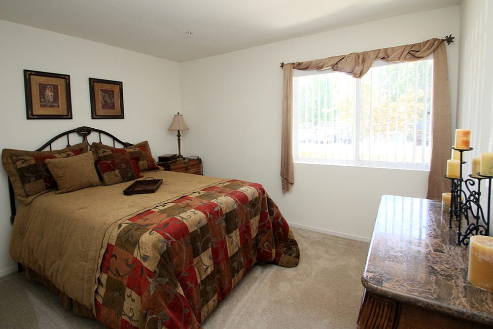 A cozy bedroom with a bed, window, and lamp.