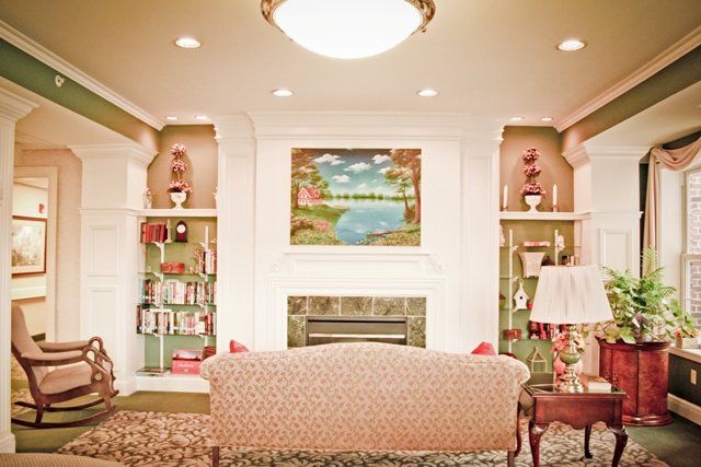 A cozy living room featuring a fireplace with built-in bookshelves and a sofa facing an artwork above the mantel.