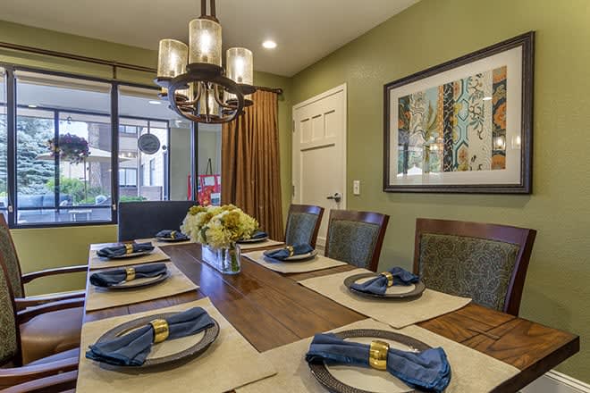 A modern dining room featuring an elegantly set table with blue napkins and a stylish chandelier overhead.