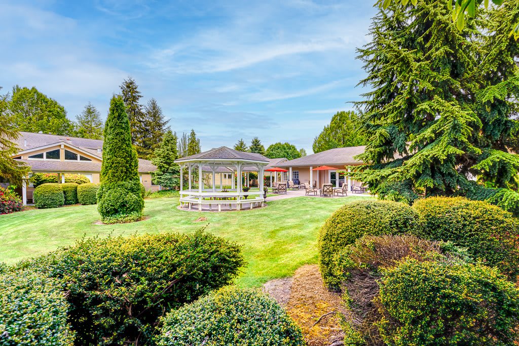 A beautifully landscaped garden with a central gazebo surrounded by lush greenery and manicured lawns.