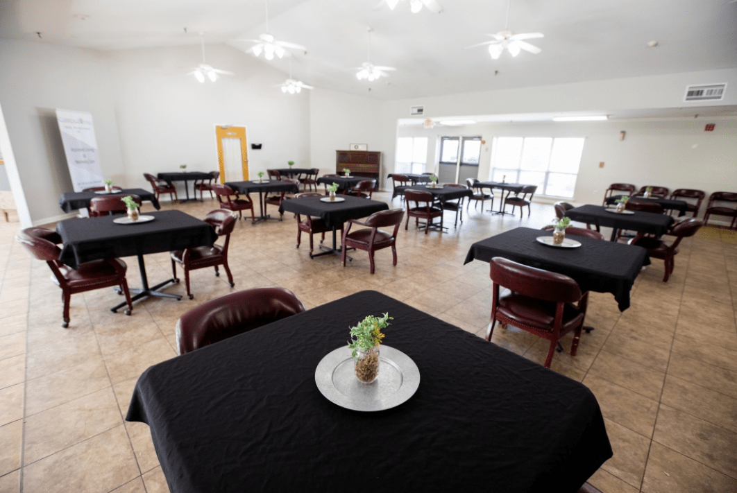 A spacious dining room with black tablecloth-covered tables and simple decor.