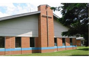 A small brick church with a prominent cross symbol on its facade.