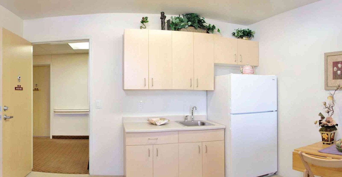 A minimalist kitchen setup with light-colored cabinets, a sink, and a white refrigerator.