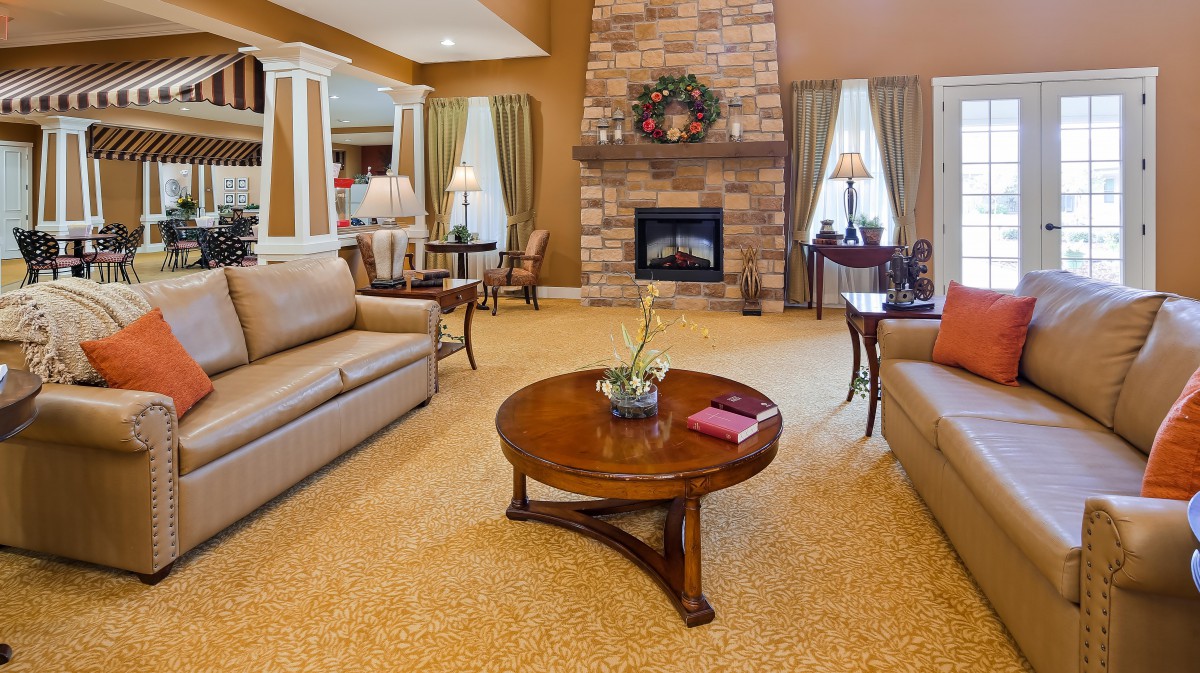 A cozy living room with sofas, a wooden coffee table, and a stone fireplace.