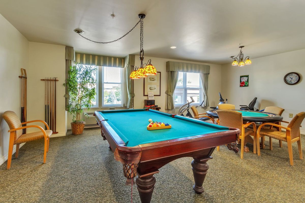 A cozy game room featuring a billiards table with cue sticks and a classic hanging light.