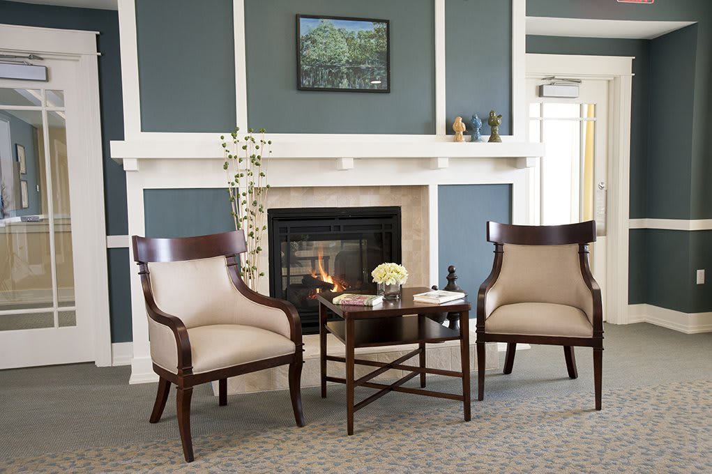 A cozy modern living room with two armchairs by a fireplace and a small table.