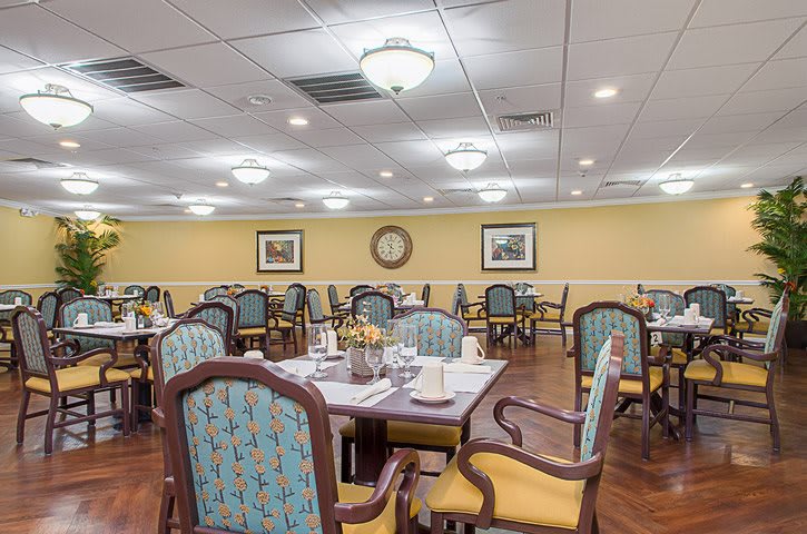 A well-lit dining room with neatly arranged tables and chairs, featuring elegant decor.