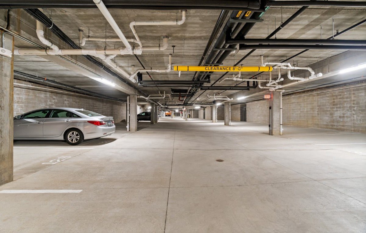 An empty underground parking garage with a single car parked on the left.