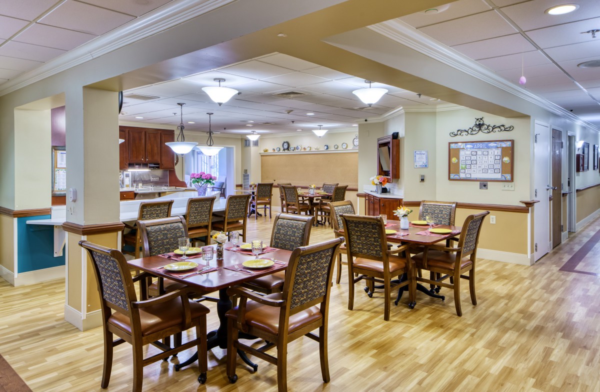 A well-lit and neatly arranged dining area with tables and chairs, featuring warm decor.