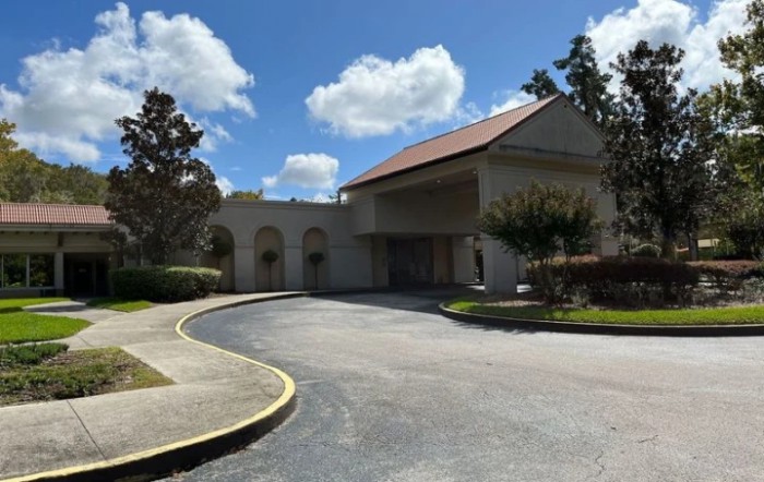 A building with a driveway on a partly cloudy day.