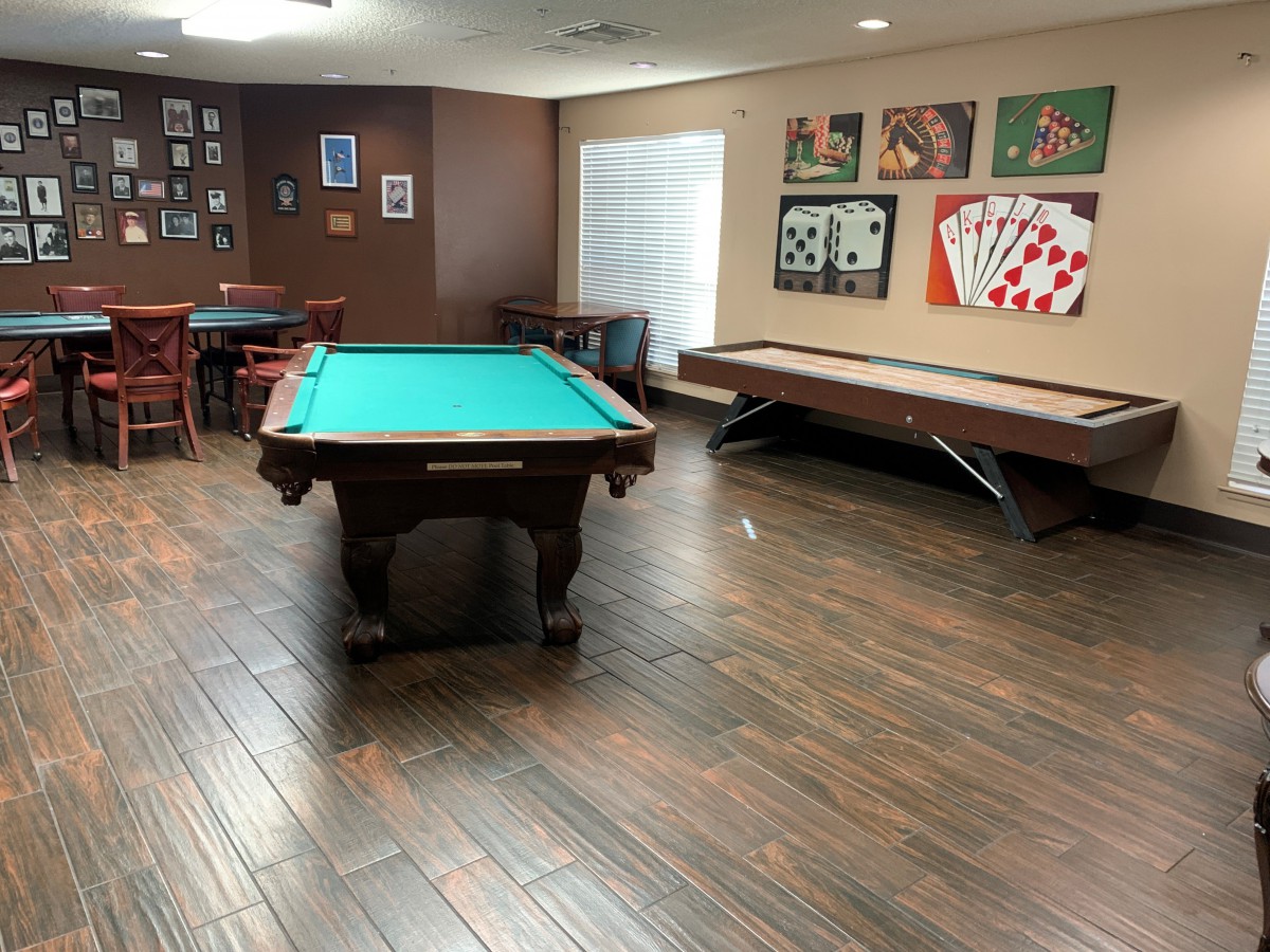 A well-equipped game room featuring a pool table and shuffleboard, adorned with card-themed artwork.
