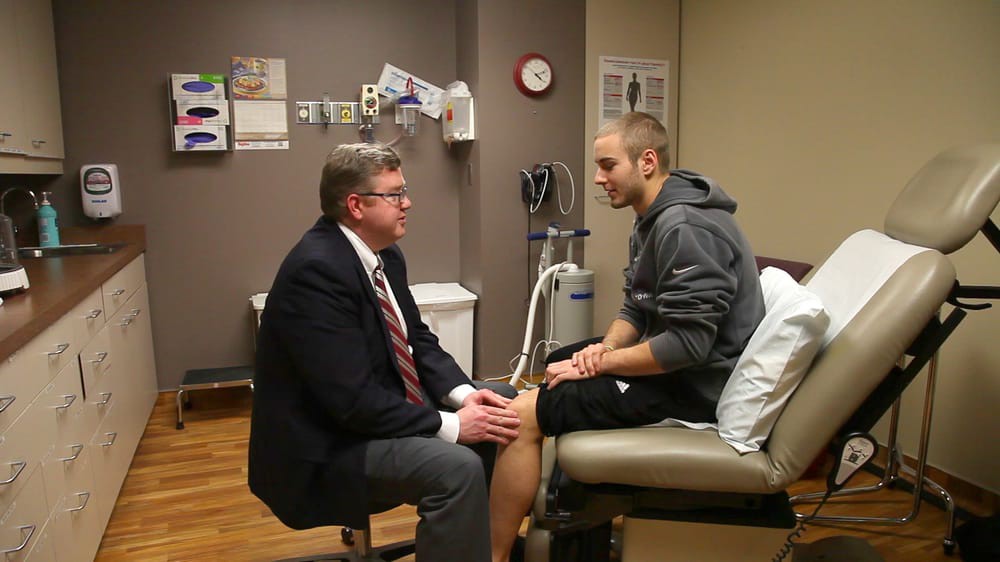 A doctor conducting a consultation with a patient in a hospital room.