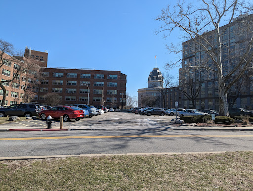 A view of a parking lot surrounded by modern buildings under a clear blue sky.