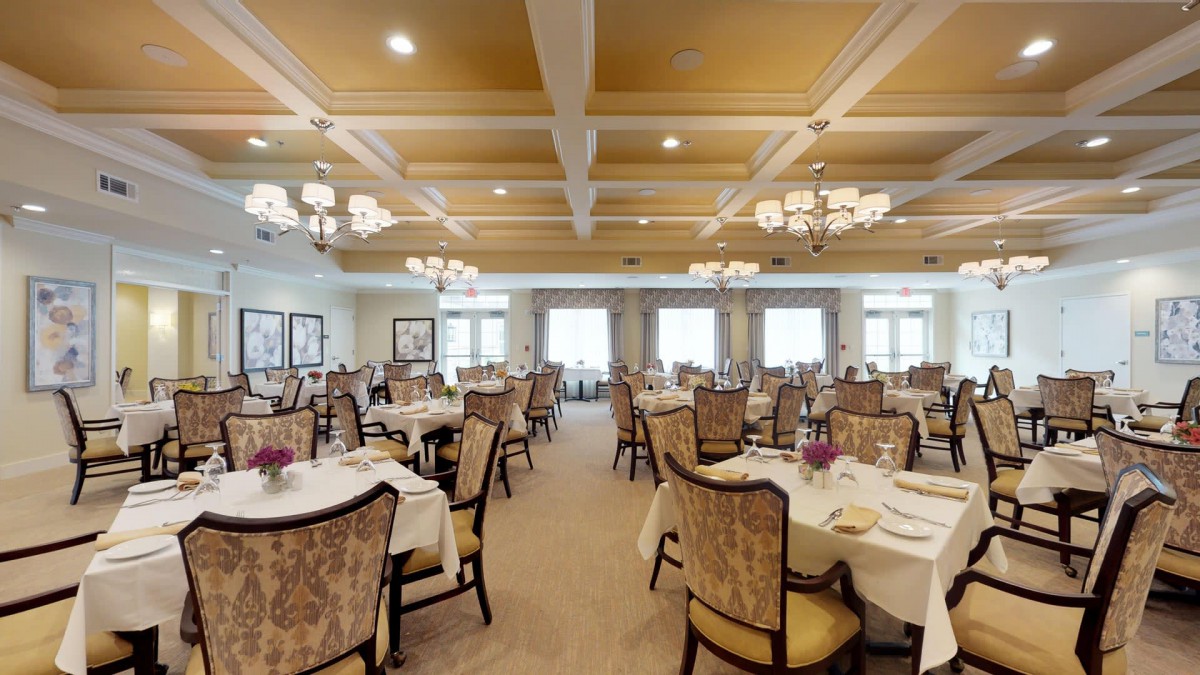 An elegant dining room with neatly arranged tables and grand chandeliers.