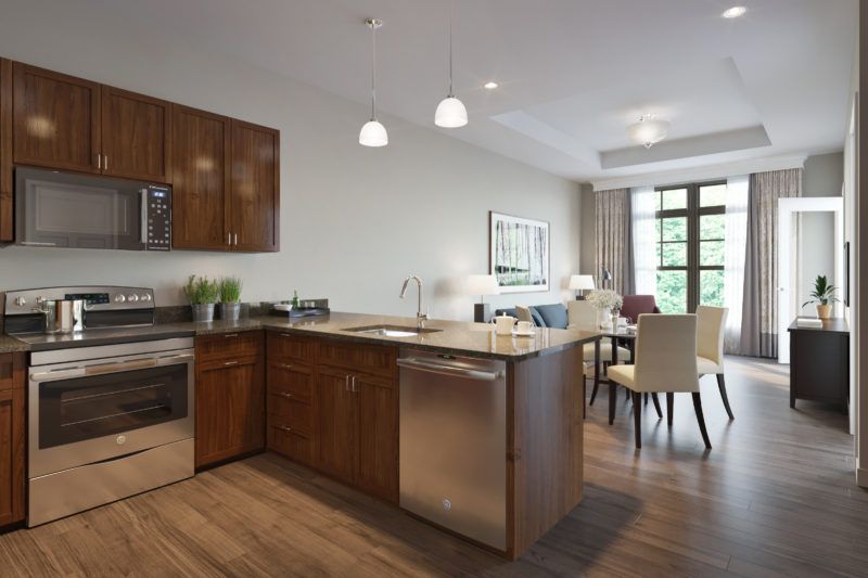 A modern open-concept kitchen with wooden cabinets, a central island, and stainless steel appliances.