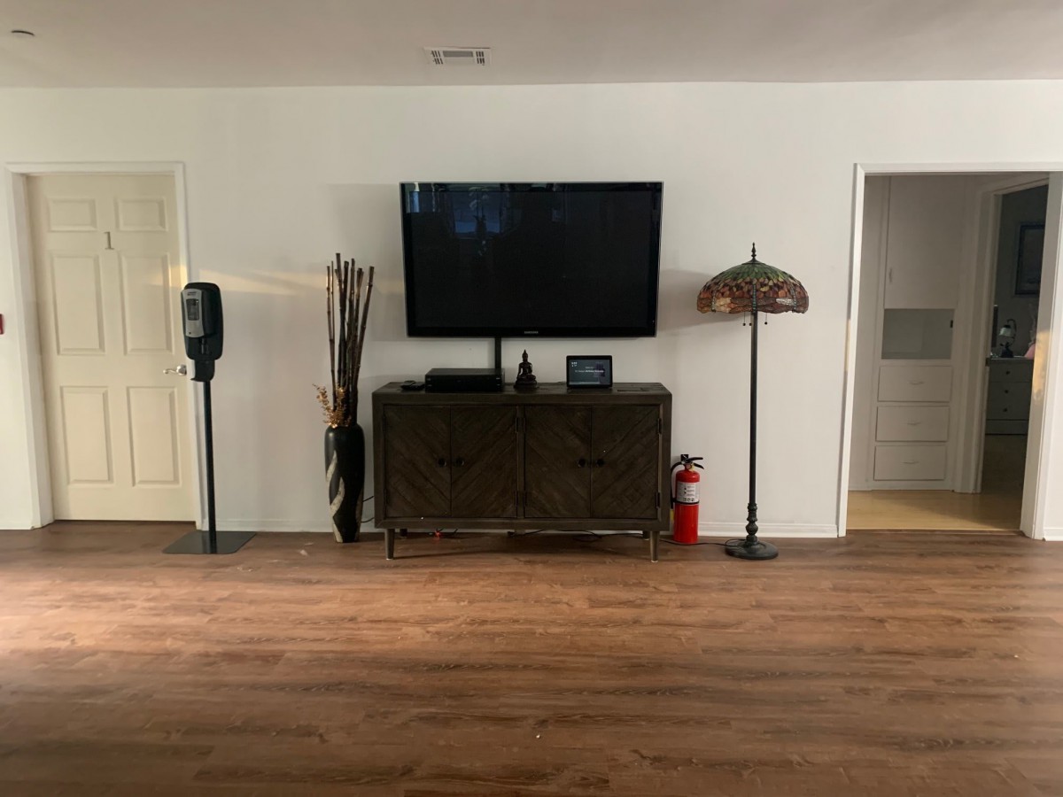 A minimalist living room setup featuring a wall-mounted television above a cabinet, with a unique lamp and decorative elements on either side.