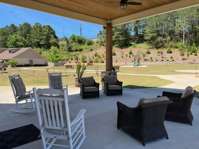 A cozy outdoor patio with comfortable seating and a view of landscaped greenery.
