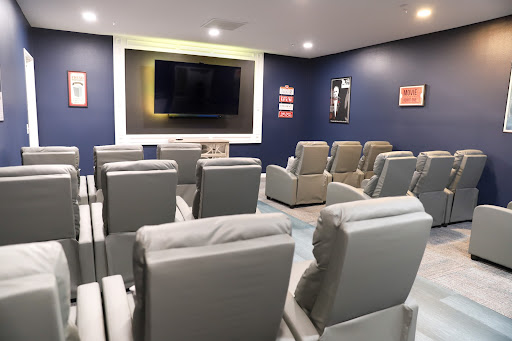 A cozy home theater room featuring comfortable seating and a large TV screen.