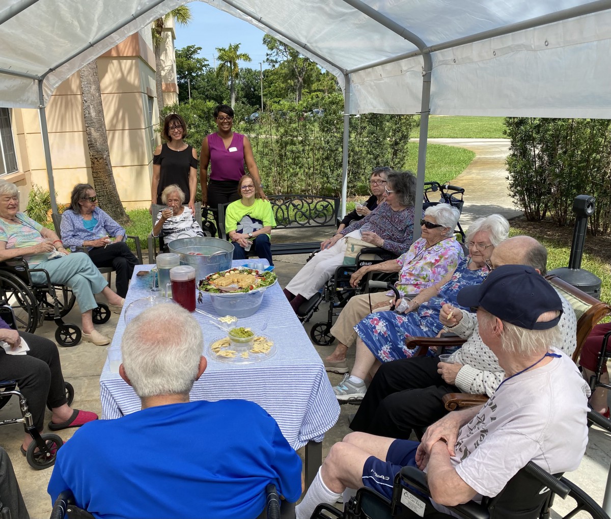 A group of seniors enjoying an outdoor gathering under a canopy.
