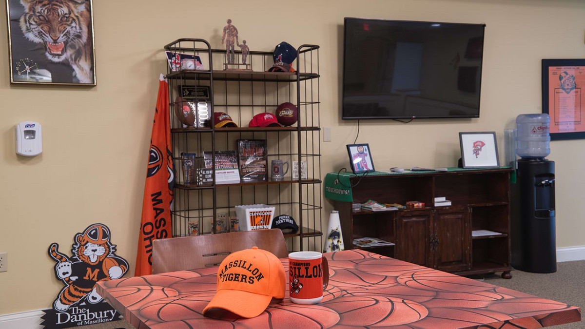 A room decorated with sports memorabilia, featuring hats, a mug, and a television.