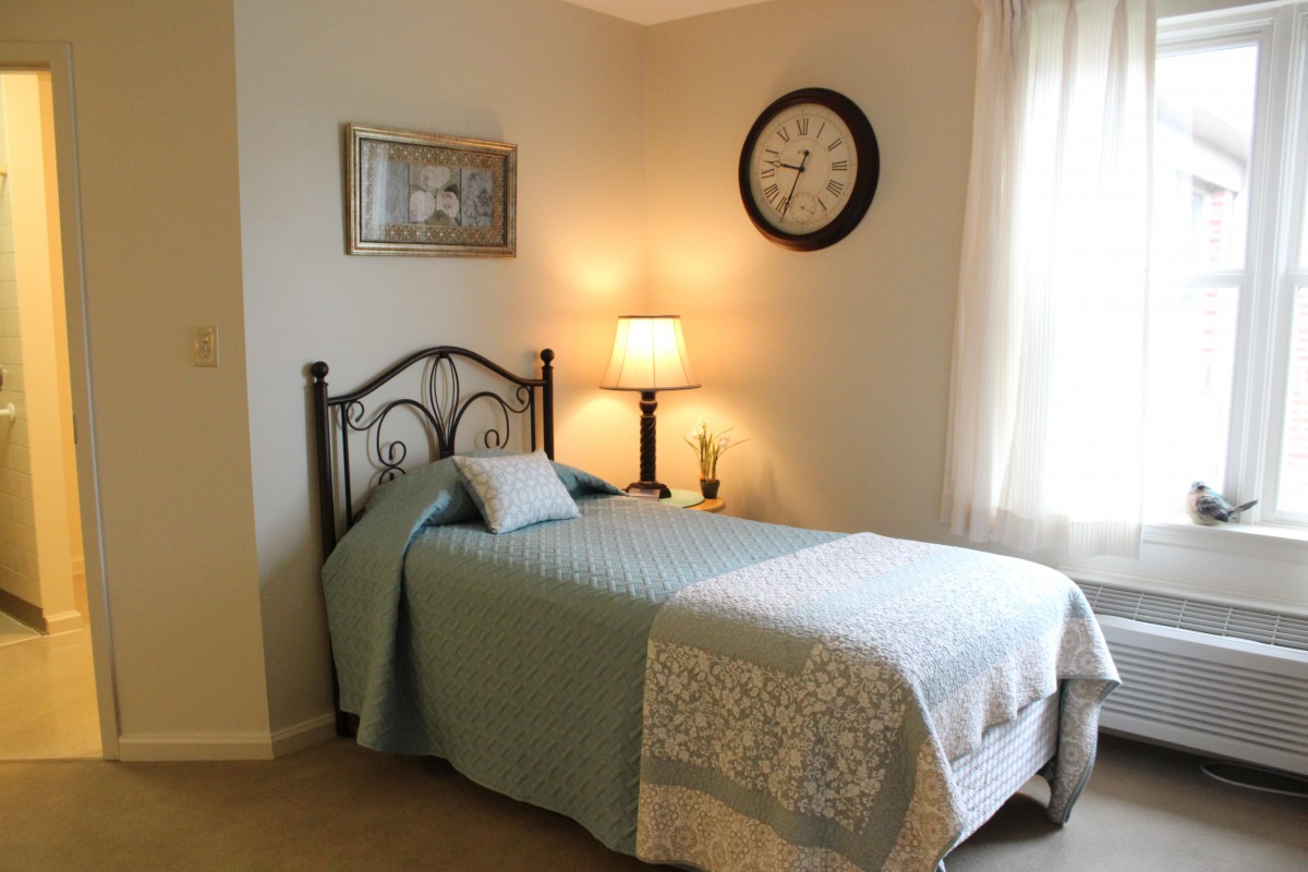 A cozy bedroom with a single bed, warm lighting, and decorative elements.