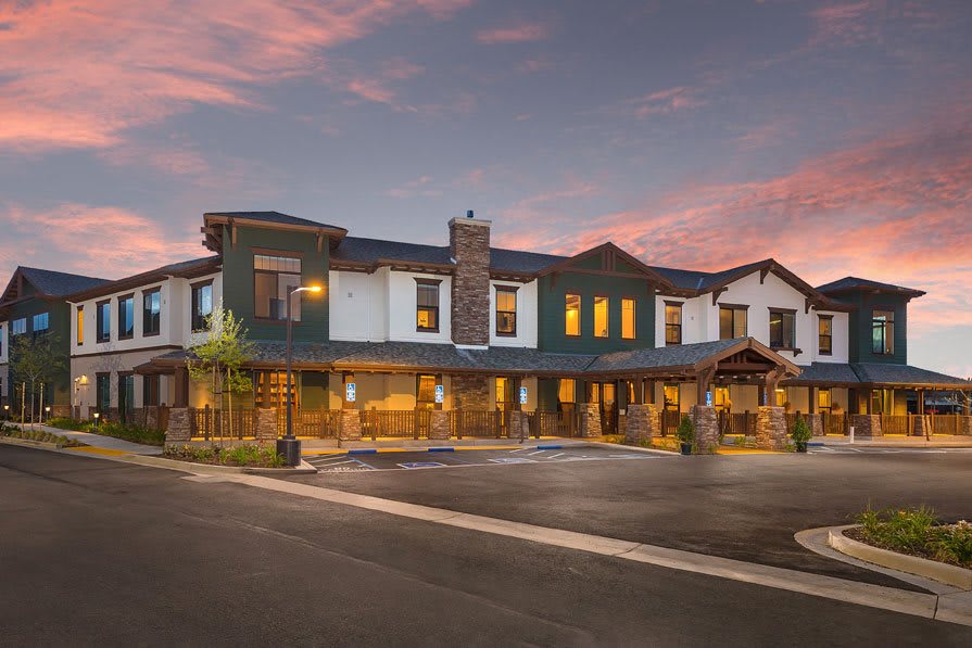 A modern hotel building under a colorful sunset sky.