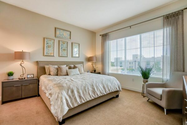 A modern and cozy bedroom with a large bed, elegant decor, and a window providing natural light.