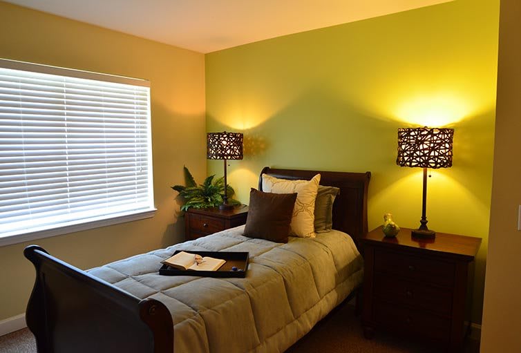 A cozy bedroom with a single bed and warm lighting.
