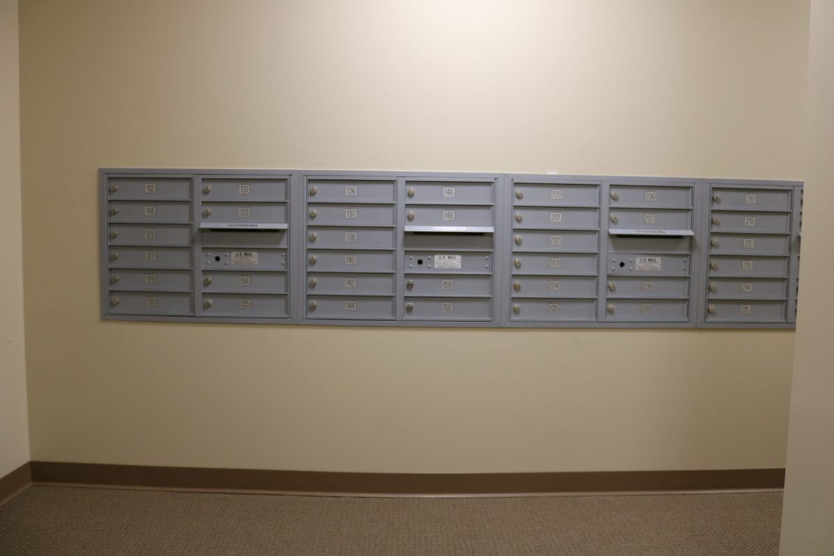 A row of wall-mounted metal mailboxes in an indoor setting.