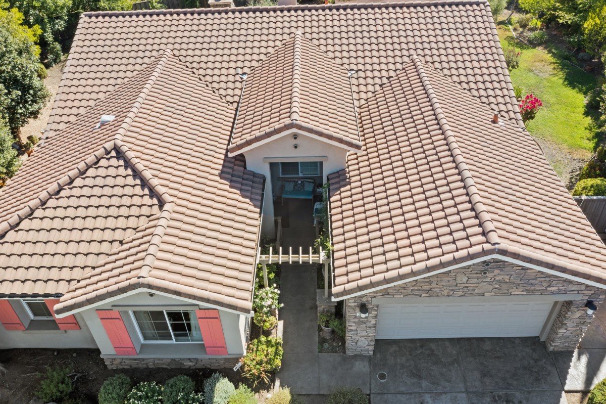 Aerial view of a suburban house with a tiled roof and landscaped front yard.