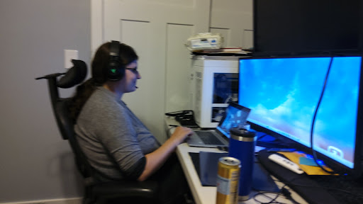A person working at a desk with multiple screens and wearing headphones.