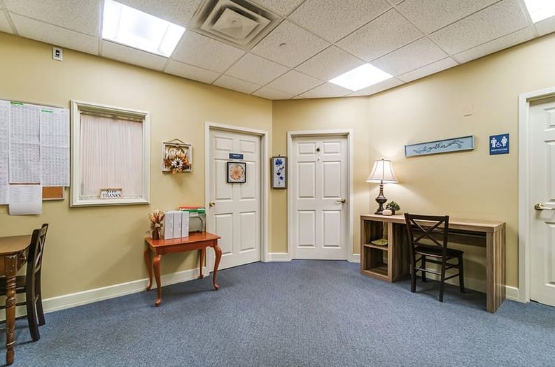 A small office waiting room with chairs, a desk, and multiple doors.