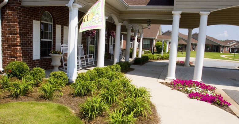 A welcoming porch with columns and neatly landscaped surroundings.