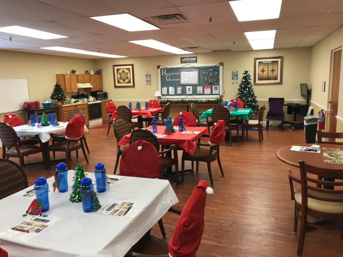 A decorated dining room with tables set for a festive occasion, featuring a Christmas tree and colorful table settings.